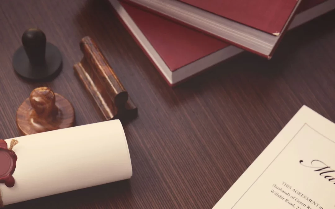 A rolled parchment sealed with wax, a stack of red books, and wooden stamps are arranged on a dark wooden table. A partially visible document titled Marriage is also present.