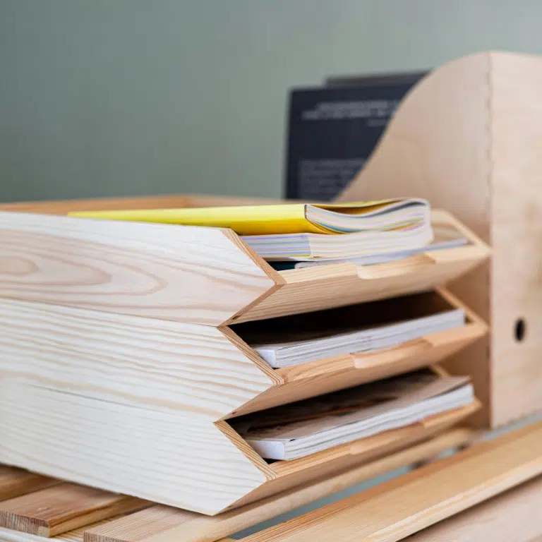 Close-up of two people at a desk, with one person signing a document on a clipboard, essential for UAE embassy attestation. The person signing wears a long-sleeved shirt, and their face is not visible. Another person, also partially visible, observes. A notepad lies nearby.