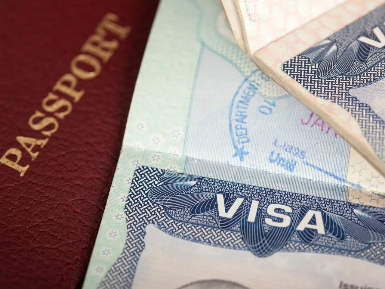 A close-up of a passport next to a visa page in another passport, showing the word VISA clearly printed on the visa document.