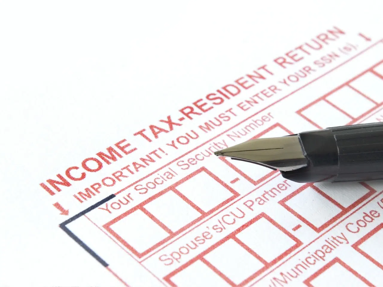 A close-up of a fountain pen resting on an income tax-resident return form, highlighting spaces for entering a social security number and other personal details.