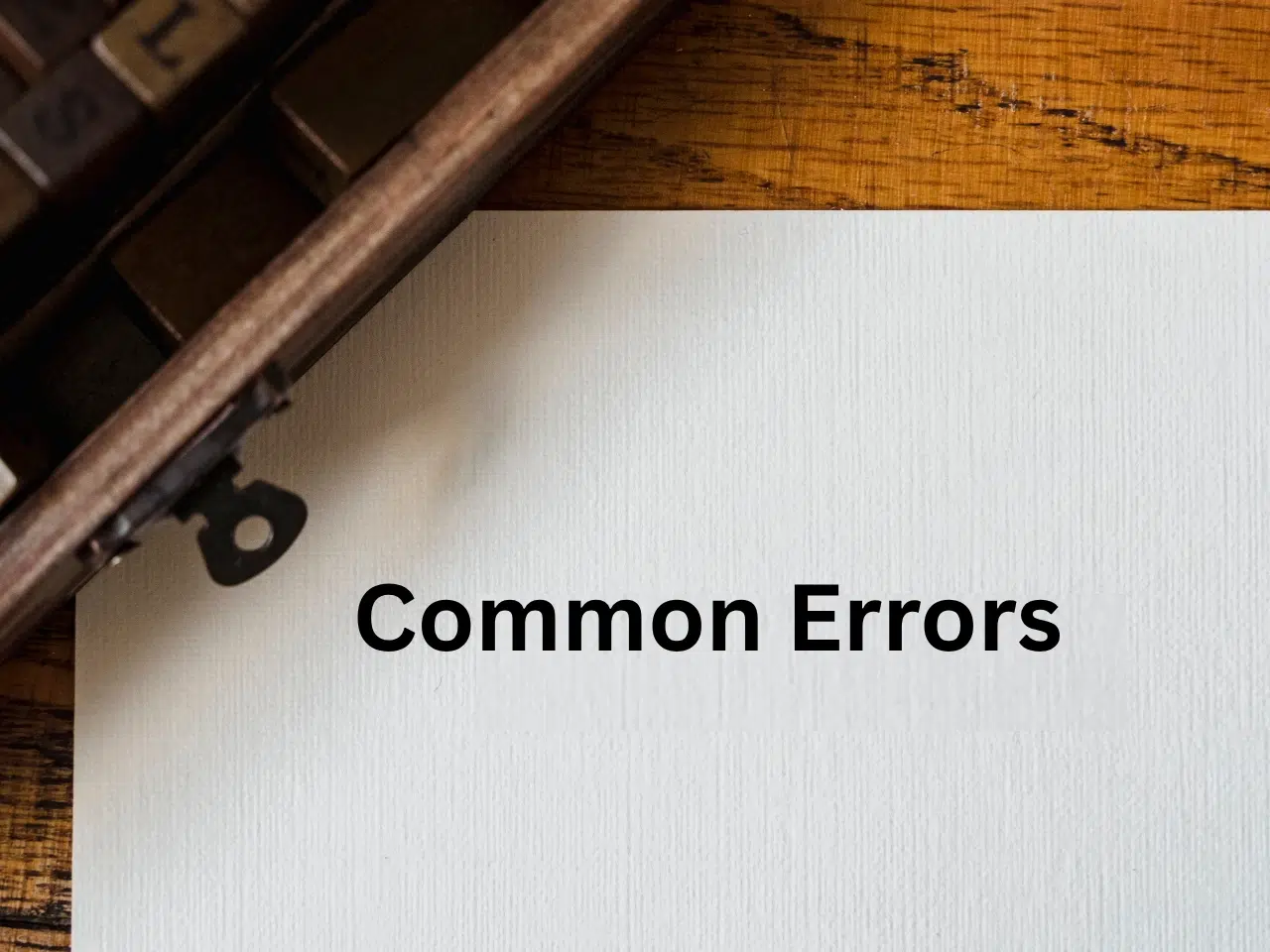 A sheet of white paper with the words Common Errors typed on it, placed on a wooden desk next to the edge of a vintage typewriter.