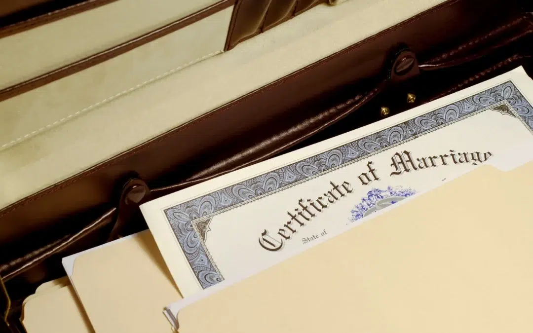 A close-up of an open briefcase containing a marriage certificate partially visible among manila file folders.