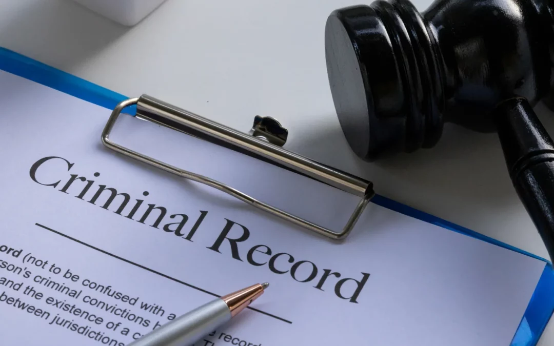 A clipboard holds a document titled Criminal Record next to a black gavel and a silver pen, suggesting a legal or judicial context.