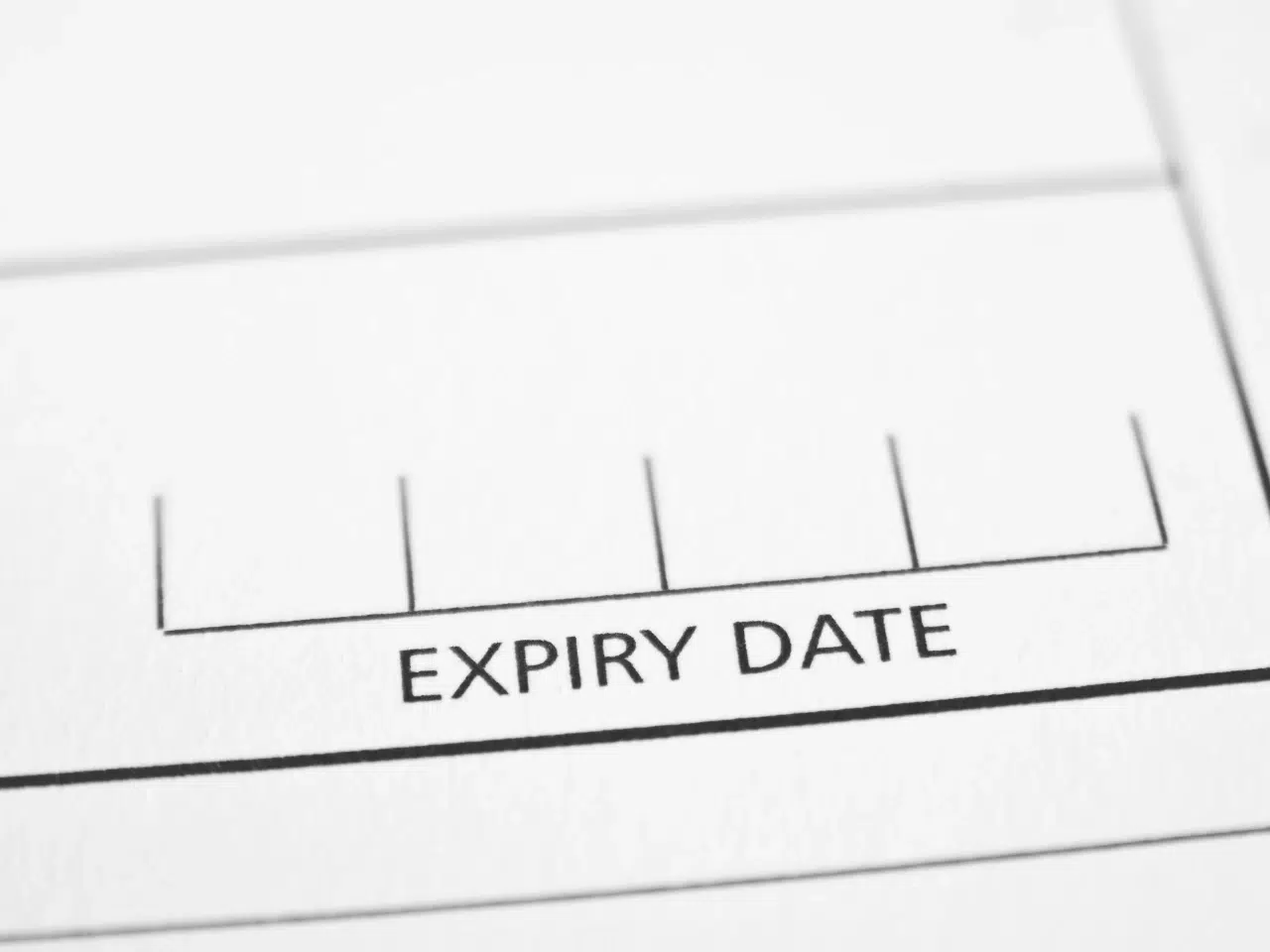 A close-up of a form with the words EXPIRY DATE printed in a box, with vertical lines indicating spaces to enter information. The image is in black and white.