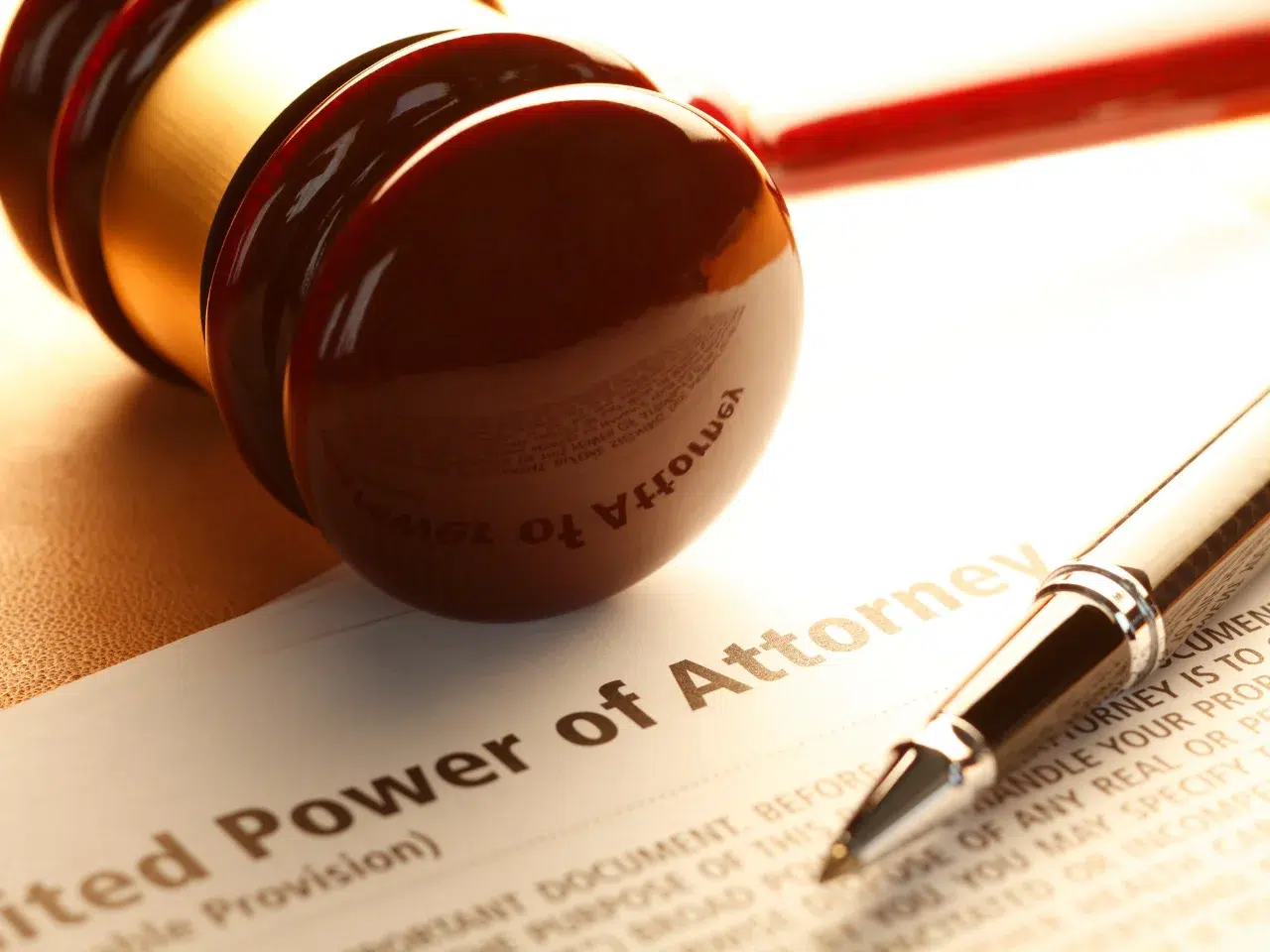 A close-up of a wooden gavel, a silver pen, and a legal document titled Power of Attorney on a desk, symbolizing legal authority and decision-making.