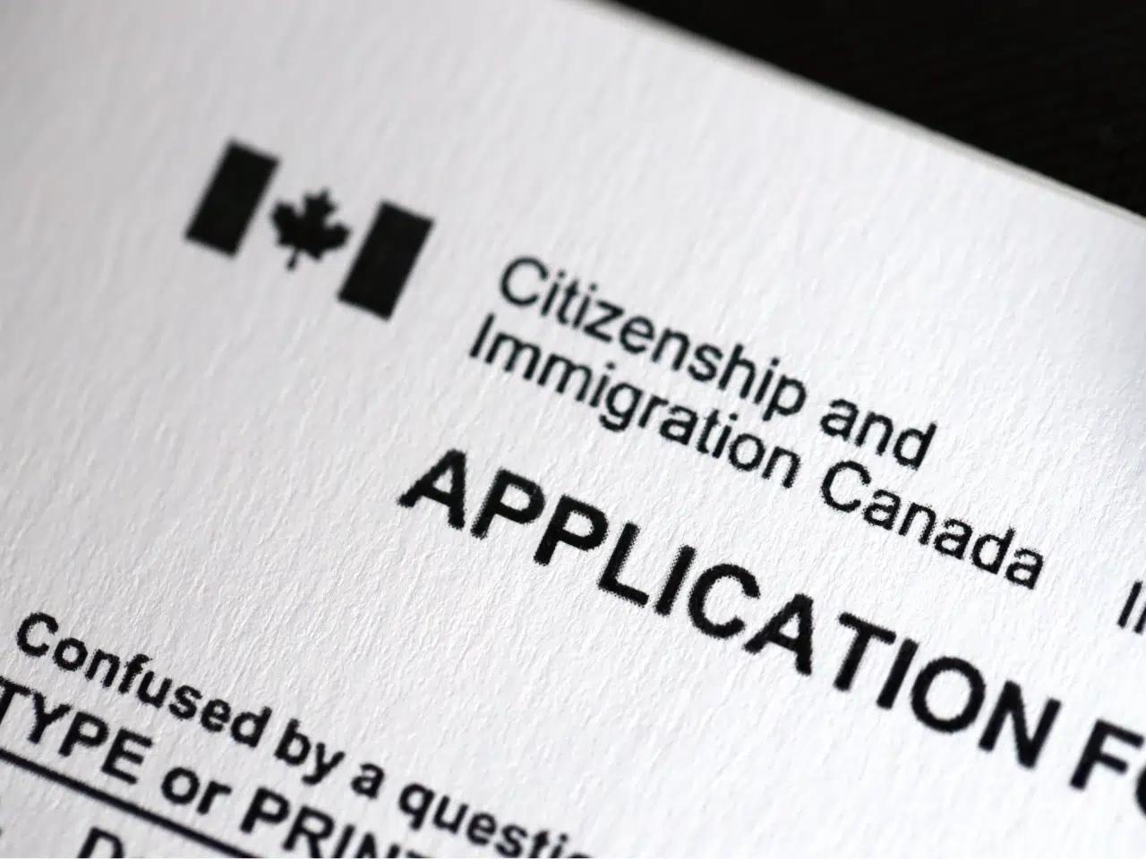 Close-up of a Citizenship and Immigration Canada application form, featuring the Canadian flag symbol and bold text on white paper.