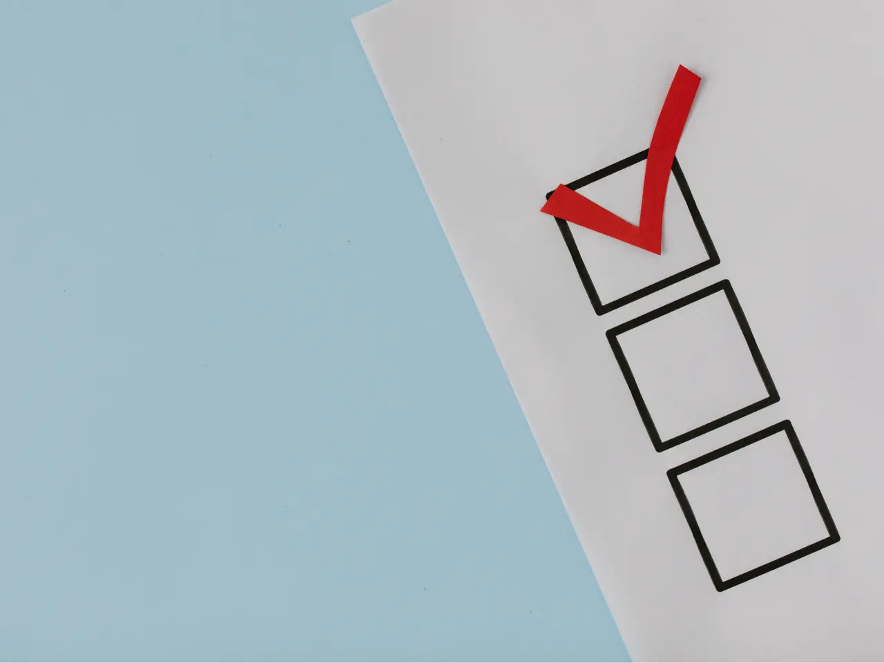 A paper with three black checkboxes, one of which is marked with a bold red checkmark, is placed on a light blue background.