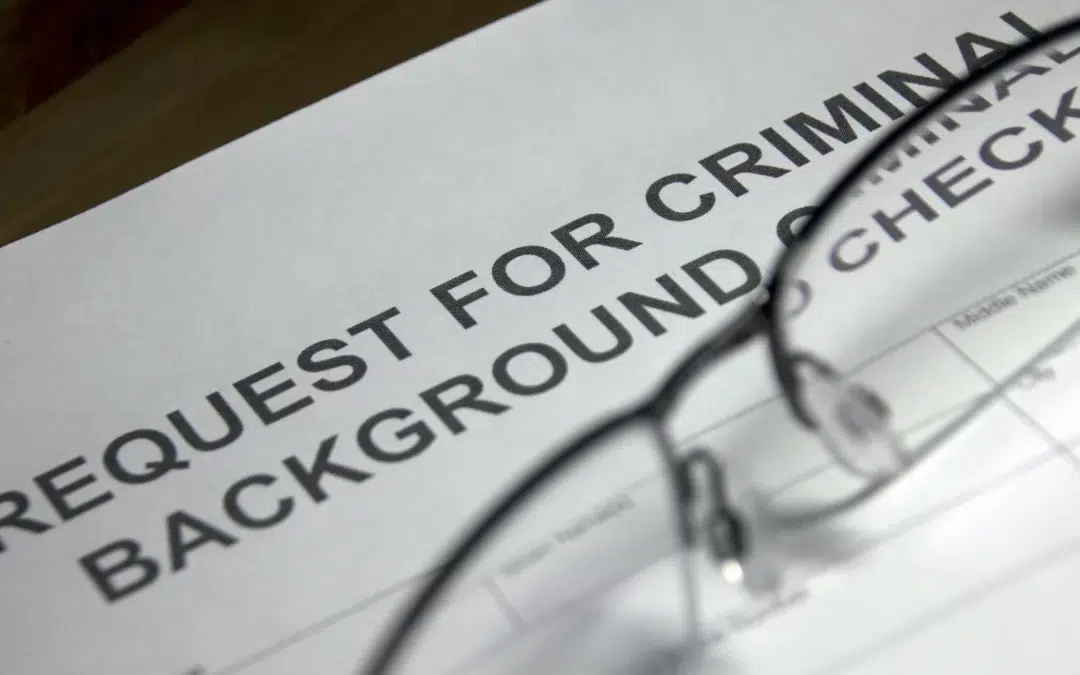 A close-up of a printed form titled Request for Criminal Background Check, with a pair of eyeglasses resting on top of the paper.