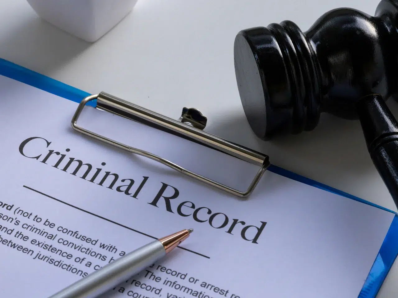 A clipboard holds a document titled Criminal Record, with a pen and a judge’s gavel nearby, symbolizing legal and judicial themes.