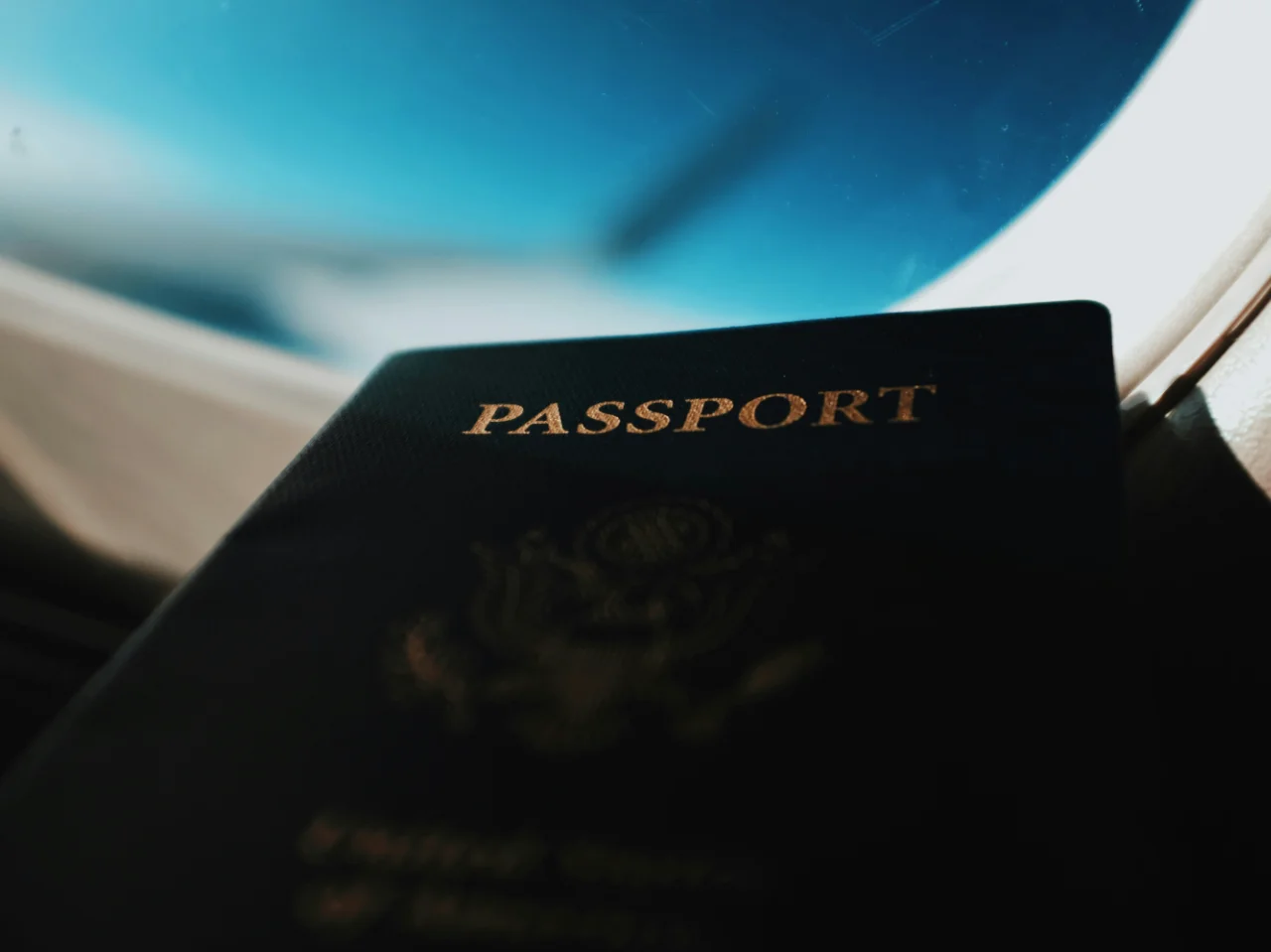 A passport against an aircraft window, representing documents sent abroad